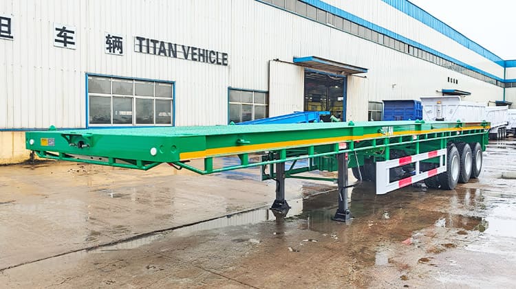 Flat Deck Trailer Price: 9500USD The flat deck trailer for sale is designed to accommodate both 20-foot and 40-foot containers, making ideal for efficient transport between ports and inland locations. The tri axle flat deck trailer for sale are engineered with structural balance in mind. When loaded, the weight is evenly distributed across the frame, minimizing concentrated stress points and reducing the chances of long term structural deformation or fatigue.  Specification of Flat Deck Trailer Dimension: 12500mm*2500mm*1630mm Loading capacity: 60 ton Side Beam: 160mm high Axles: 3 axles, TITAN brand, 13 ton Tire: 11R22.5, 12 units Suspension: mechanical suspension Leaf Spring:10 layers Bumper: 4mm thickened bumper Landing Gear: 28 ton, JOST brand Lamp: LED lamp with anti-theft net  Shipping of Flat Deck Trailer for Sale Before these 40 foot flat deck trailers are delivered, each unit undergoes thorough waterproof treatment to ensure durability during sea shipping. A protective wax layer is first applied to the surface of the flat deck trailer body which is followed by a complete waterproof cover, which offers dual-layer defense against seawater corrosion and humid salt air, conditions frequently encountered during maritime transport. Depending on buyer preferences, the tri axle flat deck trailer for sale can be transported via container shipment or roll-on/roll-off (RoRo) vessels.  Advantage of Flat Deck Trailer At the heart of the flat deck trailer for sale strength is the main beam, which is made of Q355 low-carbon, high-strength alloy steel. The material boosts the 40 foot flat deck trailer capacity to endure heavy duty loading. The key joints and frame components are welded using automatic submerged arc welding, a process that ensures deep penetration and uniform welds that not only improves structural integrity but also extends the flat deck trailer life span under demanding usage. Additional reinforcement is applied to high-stress zones, such as the gooseneck area. A double-layered steel plate is used in these sections to further increase the load-bearing ability. The structural enhancement is especially valuable when transporting bulky or concentrated cargo, as prevents bending or warping under pressure. Surface finishing is another aspect where attention to detail is evident. The tri axle flat deck trailer for sale is treated with a powder coating followed by a high-temperature baking paint process. Though the method involves higher costs compared to standard painting, it offers better resistance to scratching, sun fading, and peeling. The treatment reduces the need for frequent repainting, thereby lowering long term maintenance costs. The flat deck trailer for sale features an open deck platform, which greatly simplifies the loading and unloading of different cargo types. The flexibility is particularly useful in coastal regions like Senegal, where diverse freight conditions exist.  Since the deck is exposed to frequent contact and wear, TITAN uses a patterned steel plate on the surface to provide both durability and better traction. The deck material, 3mm thick high-strength alloy steel, is selected for its excellent load support and resistance to rust, helping the trailer retain its appearance and functionality in moist or saline environments. Each axle on the 40 foot flat deck trailer is rated to handle 13 tons, providing strong support for high-capacity freight. These axles are built to resist bending and fatigue, and they perform reliably on gravel or uneven roads. The durable construction helps mitigate damage from vibration and prevents failures caused by consistent overloading or repeated impacts. The suspension system also plays a critical role in performance. The 40 foot flat deck trailer uses a mechanical suspension setup with multi-leaf springs and a 70mm central balance pin. Reinforcements on all sides—front, rear, and both flanks—help maintain form and absorb shocks effectively. The robust suspension configuration ensures stability and preserves the structural frame even under the heat and rough terrain commonly found in Senegal. In addition, the lighting system on the tri axle flat deck trailer for sale has been thoughtfully upgraded. It includes a complete set of LED lights, which outperform traditional bulbs in energy use, brightness, and lifespan. These LEDs are resistant to shaking and moisture, ensuring better visibility in Senegal poor weather or during nighttime operations. TITAN also integrates an anti-theft feature into the lighting system, offering an added level of security when the flat deck trailer for sale is parked or in transit.